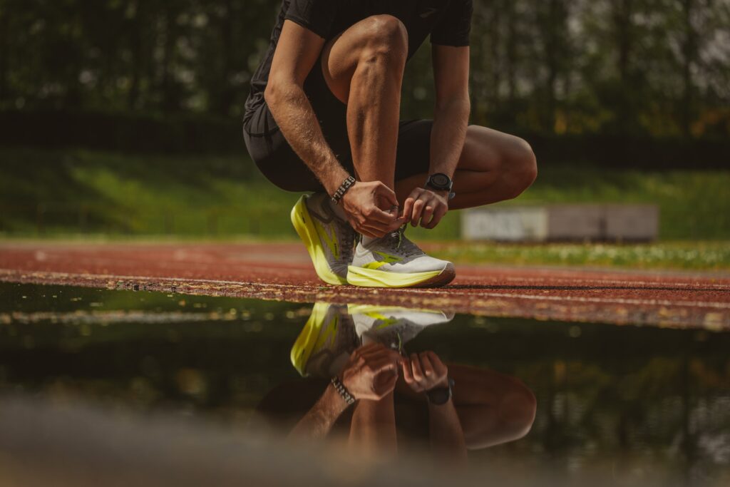 A man tying his shoelace; getting ready to run (Success Through Failure episode 313: How to Leverage Two Laws of Persuasion Psychology To Trick Yourself Into Doing What You Don’t Want To Do)